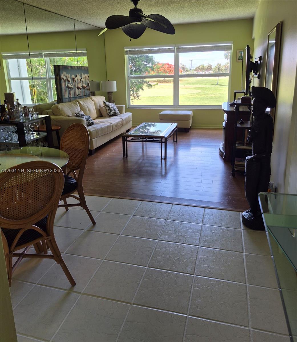 A living and dining area features wood and tile flooring, a ceiling fan, and large windows — 7797 Golf Cir Dr # 206, Margate FL 33063, MARGATE, FL