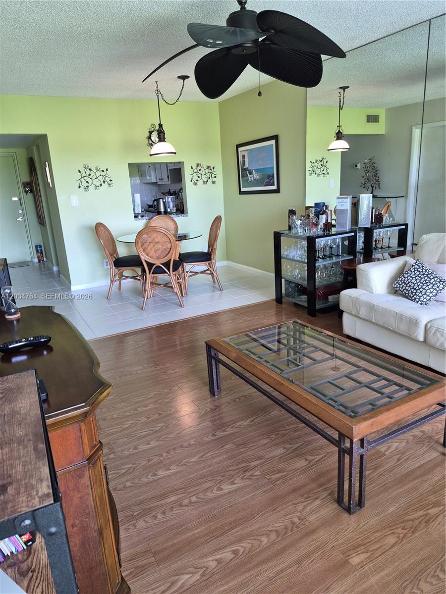 A living room with wood-look flooring, a glass coffee table, and an adjacent dining area — 7797 Golf Cir Dr # 206, Margate FL 33063, MARGATE, FL