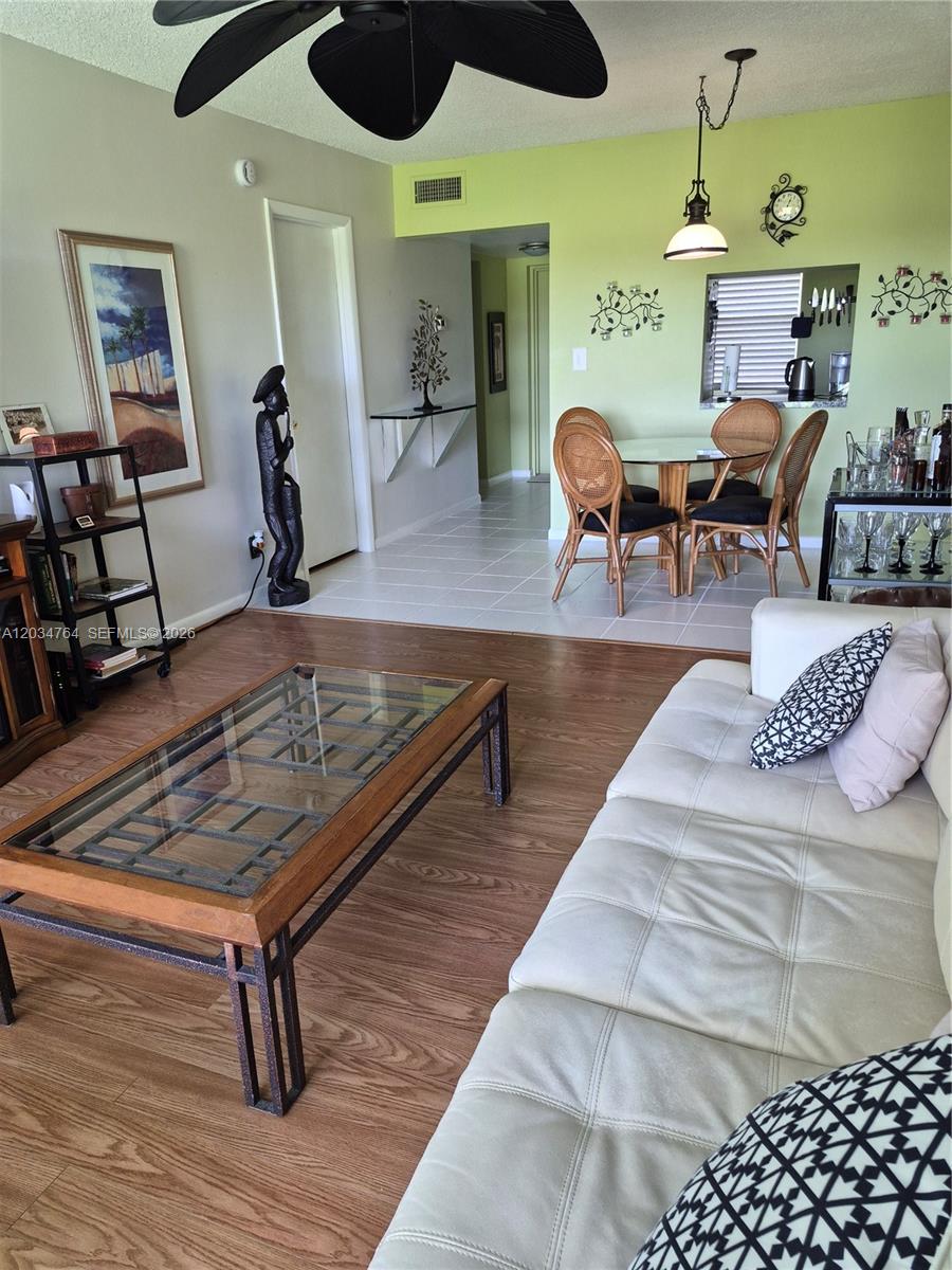 A living room with wood-look flooring, a glass coffee table, and an adjacent dining area — 7797 Golf Cir Dr # 206, Margate FL 33063, MARGATE, FL
