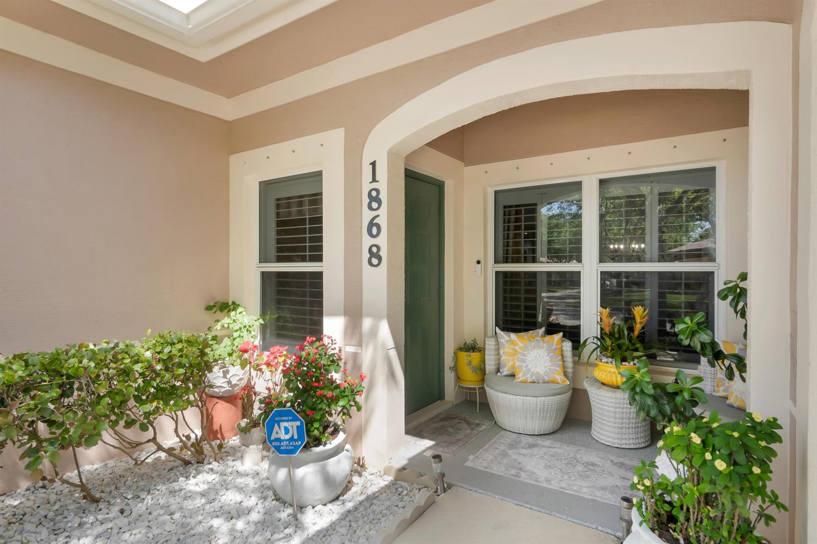 A front porch features a green door, white wicker chairs, potted plants, and white gravel — 1868 E Sanderling Lane, Fort Pierce FL 34982, FORT PIERCE, FL
