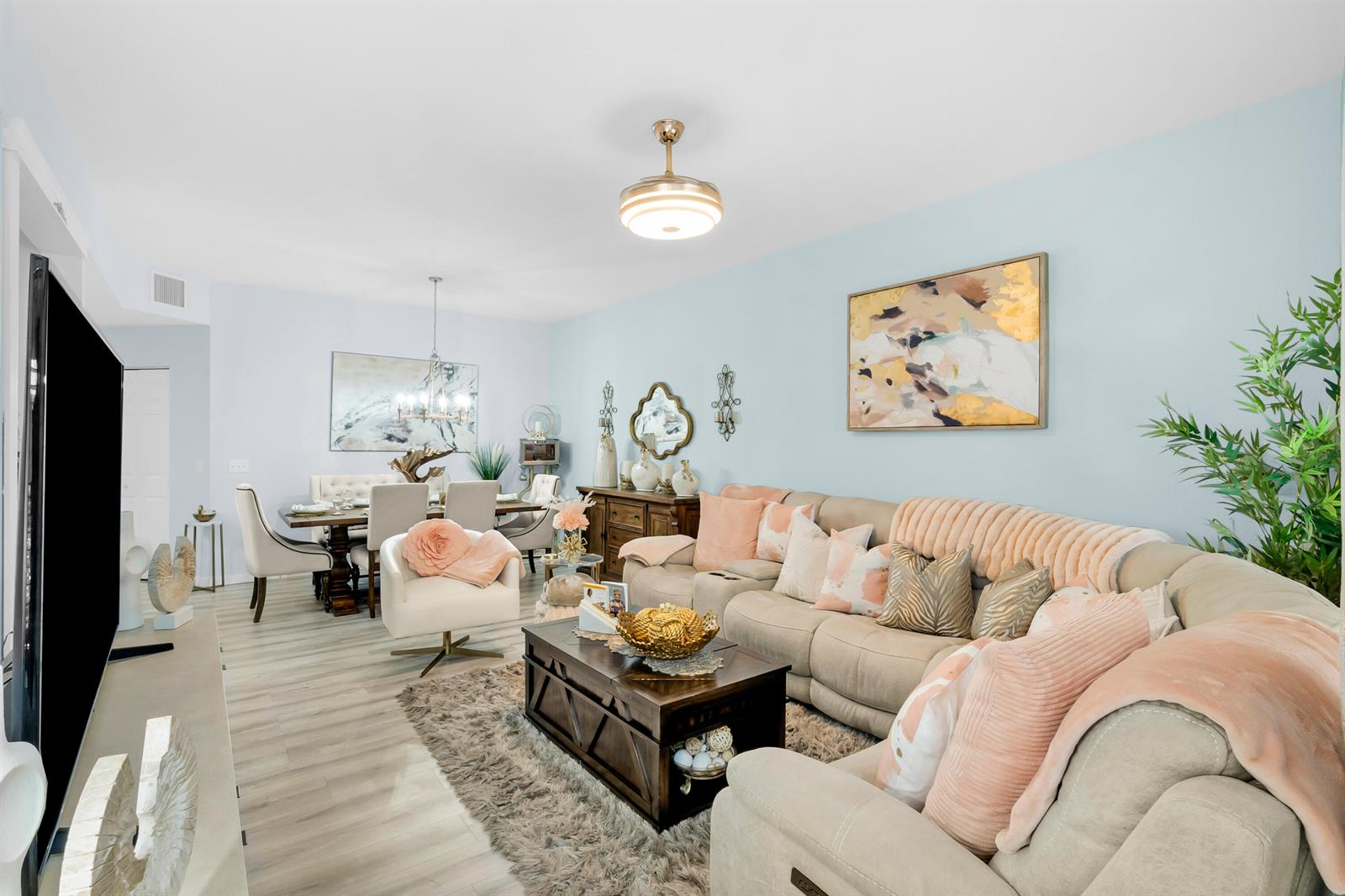 A living room with light blue walls, a beige sectional sofa, and an adjacent dining area — 1868 E Sanderling Lane, Fort Pierce FL 34982, FORT PIERCE, FL