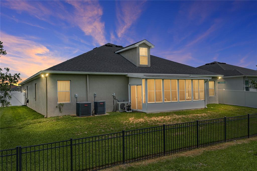 The exterior rear view of a house features a sunroom, two AC units, and fencing — 1444 CYPRESS VIEW LANE, LAKELAND, FL