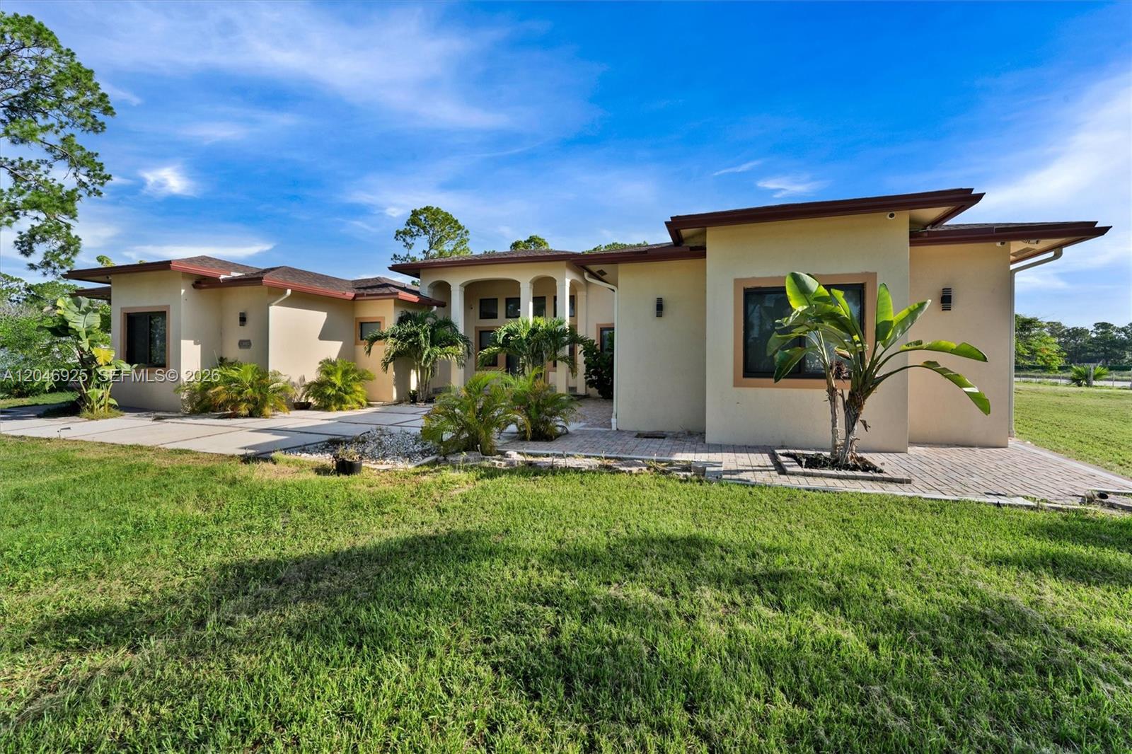 A single-story house with a beige stucco exterior, a flat roof, and a paved courtyard — 13085 N 78th Pl N, Palm Beach FL 33412, PALM BEACH, FL