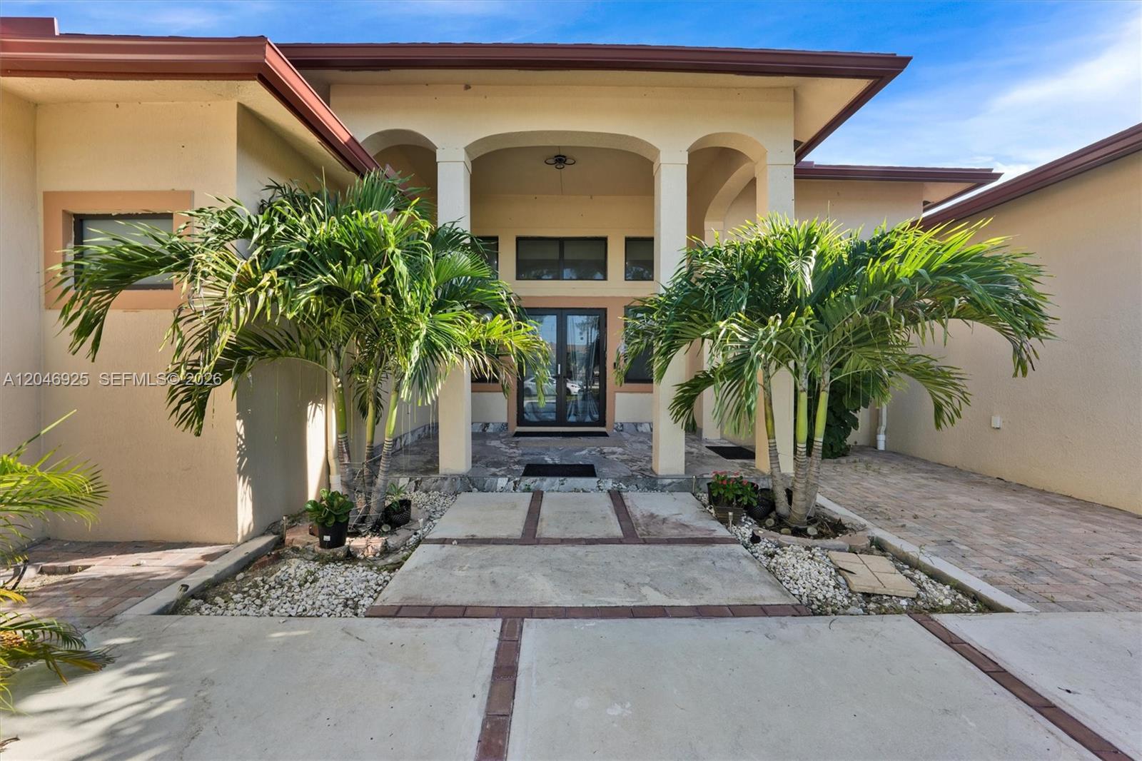 The exterior of a house features a covered entryway with arched columns and palm trees — 13085 N 78th Pl N, Palm Beach FL 33412, PALM BEACH, FL