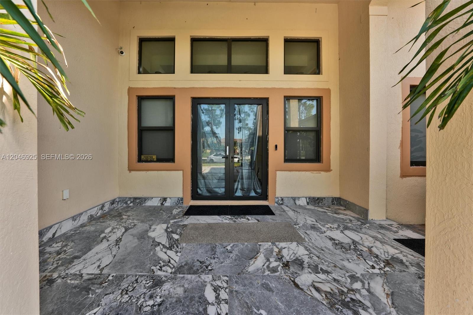 A covered entryway features double glass doors, marble flooring, and surrounding windows — 13085 N 78th Pl N, Palm Beach FL 33412, PALM BEACH, FL
