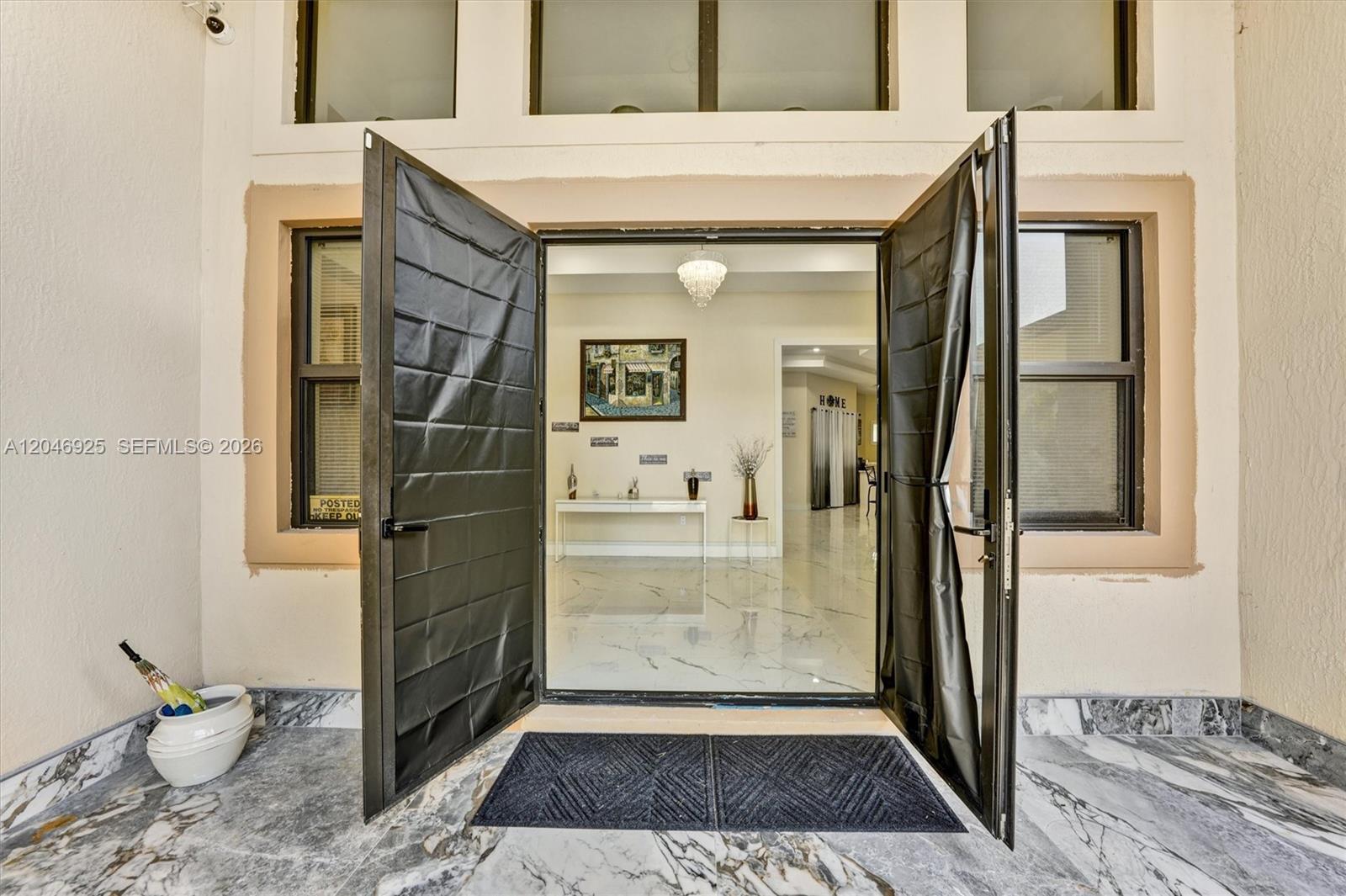 An open double door reveals a bright foyer with marble flooring and a crystal chandelier — 13085 N 78th Pl N, Palm Beach FL 33412, PALM BEACH, FL