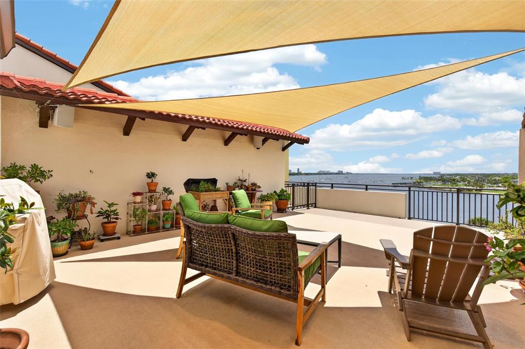 A rooftop terrace features a shaded seating area, potted plants, and a view of water — 744 MARINA POINT DRIVE UNIT 7440, DAYTONA BEACH, FL