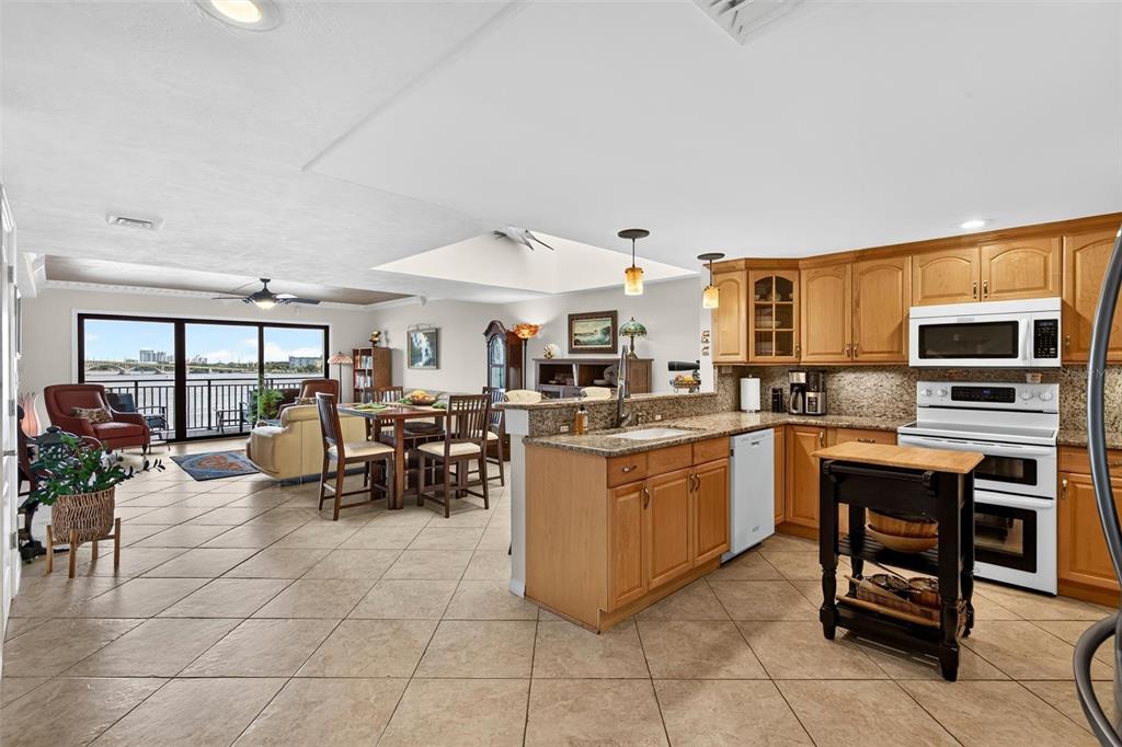 An open-concept kitchen and living area with tile floors, wooden cabinets, and a balcony view — 744 MARINA POINT DRIVE UNIT 7440, DAYTONA BEACH, FL