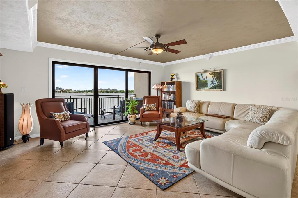 A living room with tile floors, a sectional sofa, two armchairs, and a waterfront balcony view — 744 MARINA POINT DRIVE UNIT 7440, DAYTONA BEACH, FL