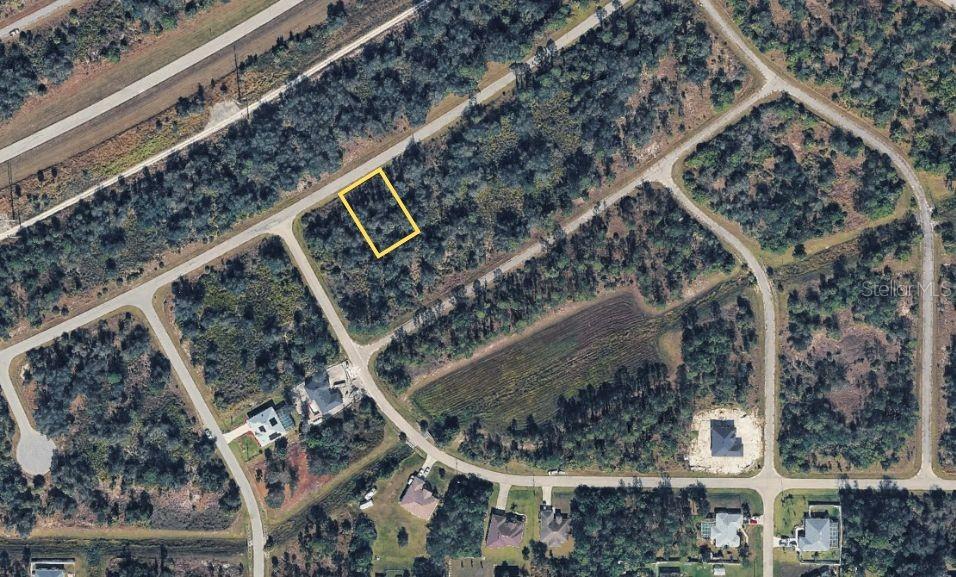 An aerial view shows a vacant, wooded residential lot outlined in yellow within a subdivision — WYLAM DRIVE, NORTH PORT, FL