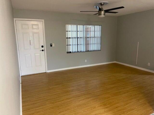An empty room features light gray walls, wood-look flooring, a ceiling fan, and a door — 4237 Oak Terrace Drive, FL 33463, FL