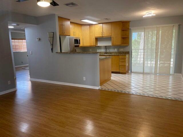 A kitchen with wood cabinets and a breakfast bar opens to a tiled dining area — 4237 Oak Terrace Drive, FL 33463, FL