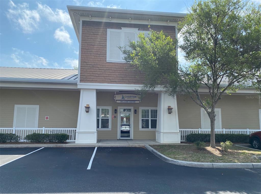 The exterior of a tan commercial building features a central entrance with a white sign — 737 COUNTY ROAD 466, LADY LAKE, FL