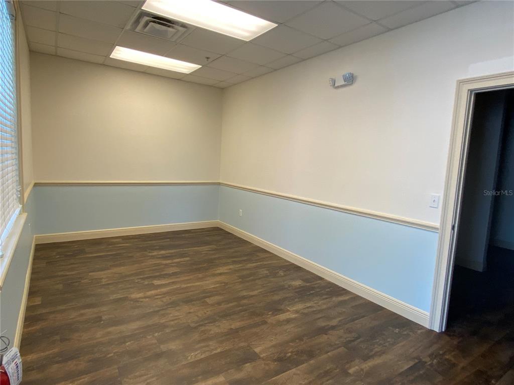 An empty office room features light blue wainscoting, white walls, and dark wood-look flooring — 737 COUNTY ROAD 466, LADY LAKE, FL