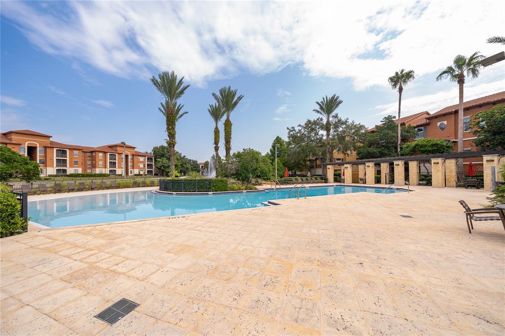 A swimming pool with a fountain is surrounded by a stone deck and apartment buildings — 6141 METROWEST BOULEVARD UNIT 305, ORLANDO, FL