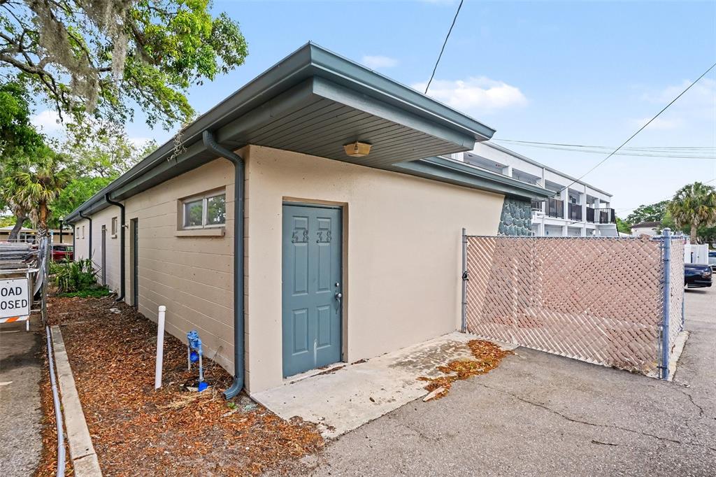 A beige exterior building with a blue door and a chain-link fence — 5838 MAIN STREET, NEW PORT RICHEY, FL