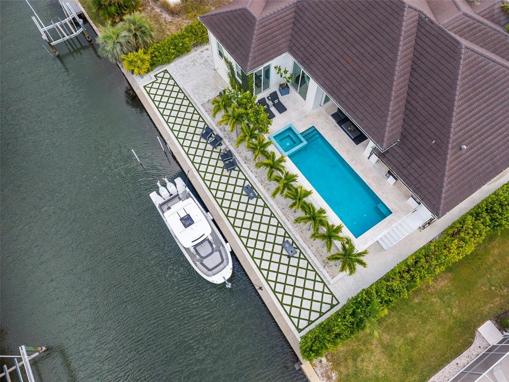 An aerial view shows a waterfront house with a pool, patio, and docked boat — 1643 STANFORD LANE, SARASOTA, FL