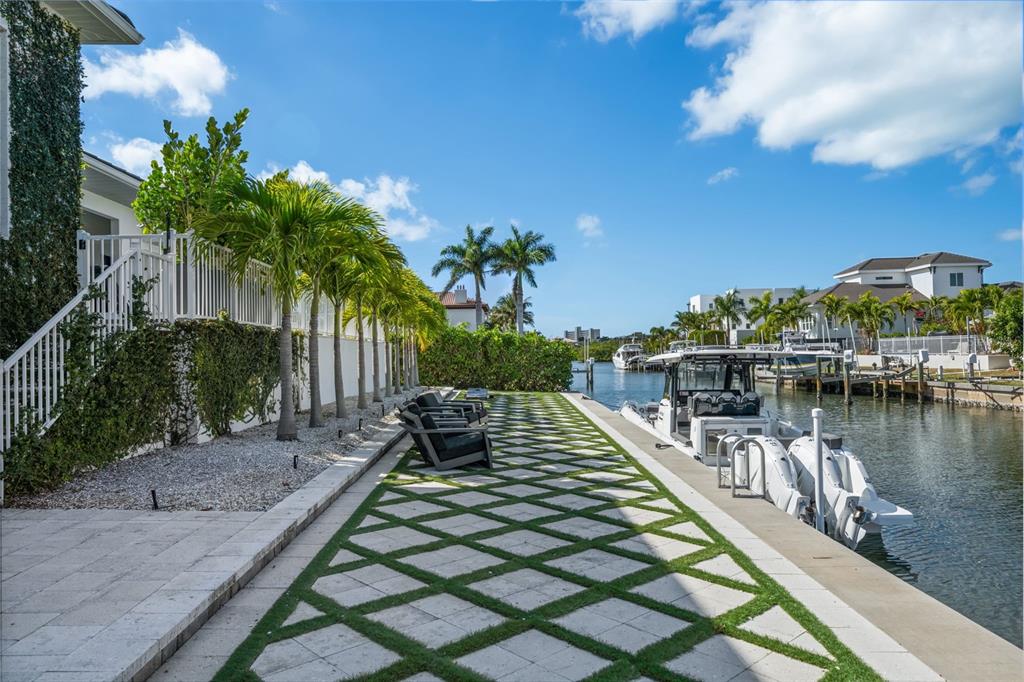 A waterfront house with a pool, palm trees, and a boat docked in the foreground — 1643 STANFORD LANE, SARASOTA, FL