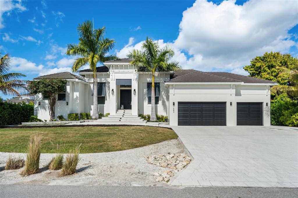 The front entrance of a white house features a dark double door, shutters, and palm trees — 1643 STANFORD LANE, SARASOTA, FL