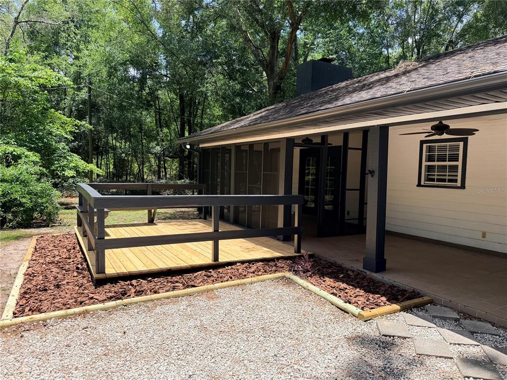 A wooden deck with railings sits next to a covered patio and a screened porch — 5309 NE 60TH AVENUE, HIGH SPRINGS, FL