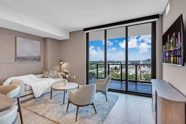 A modern living room features a sofa, two armchairs, a coffee table, and floor-to-ceiling windows — MIAMI BEACH, FL
