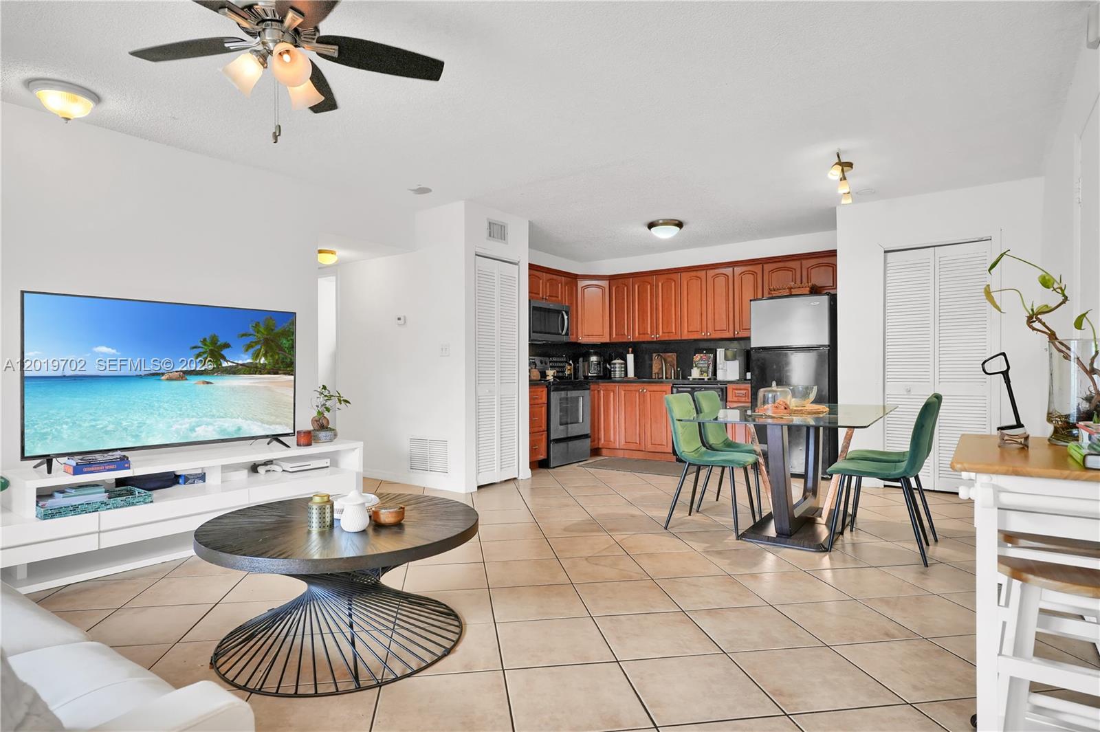 An open-concept living and dining area features tile flooring, wood cabinets, and a ceiling fan — 10786 N Kendall Dr # D18, Miami FL 33176, MIAMI, FL