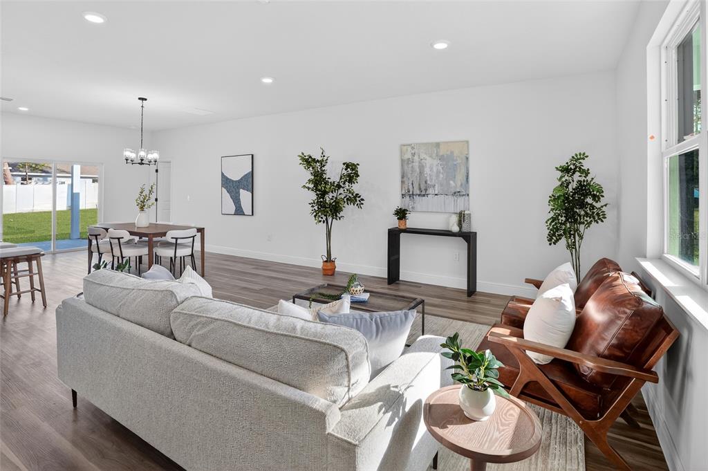 An open-concept living and dining area features light wood-look flooring, white walls, and modern furniture — 8162 N MALTESE DRIVE, CITRUS SPRINGS, FL