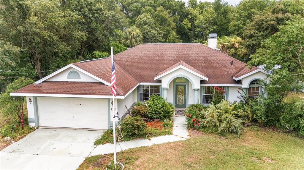 A single-story house with a brown roof, white garage, and a flag pole in front — 133 N MCGOWAN, CRYSTAL RIVER, FL
