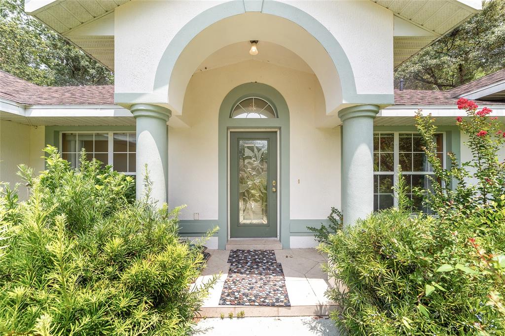 The front entrance features a green door with a glass insert under a covered porch — 133 N MCGOWAN, CRYSTAL RIVER, FL
