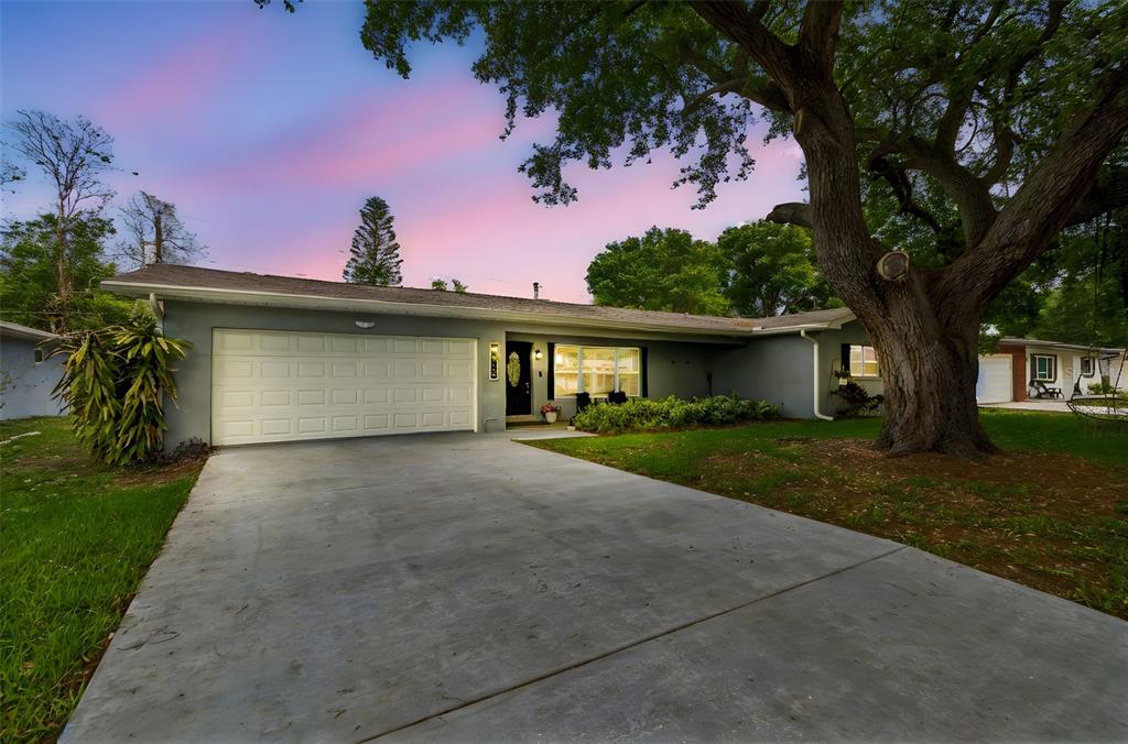 A single-story gray house with a two-car garage and a large tree in the yard — 1618 BARRY ROAD, CLEARWATER, FL