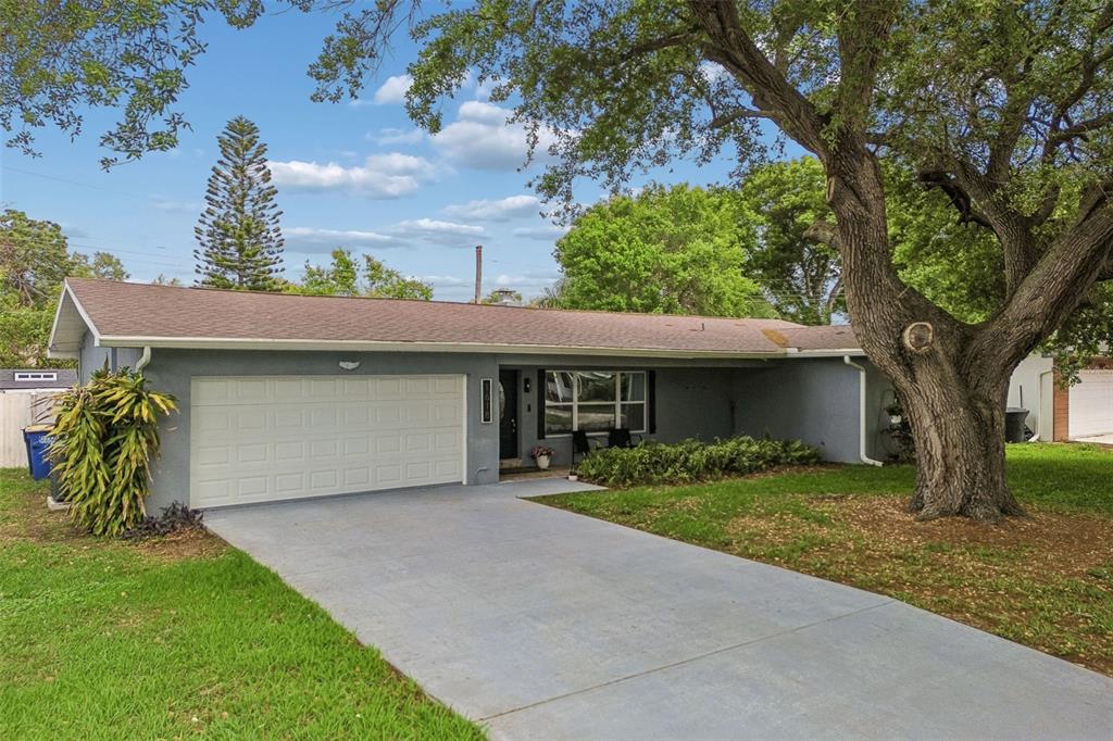 A single-story gray house with a two-car garage and a large tree in the yard — 1618 BARRY ROAD, CLEARWATER, FL