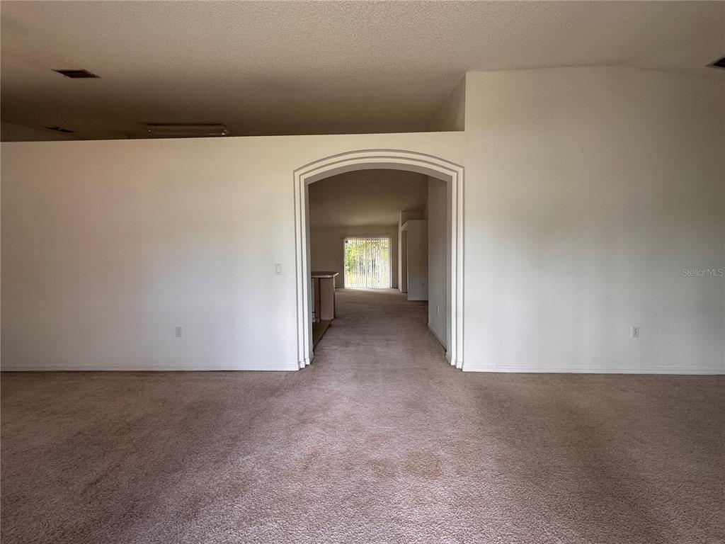A carpeted living room features a large arched entryway leading to a dining area — 33 RYBARK LANE, PALM COAST, FL