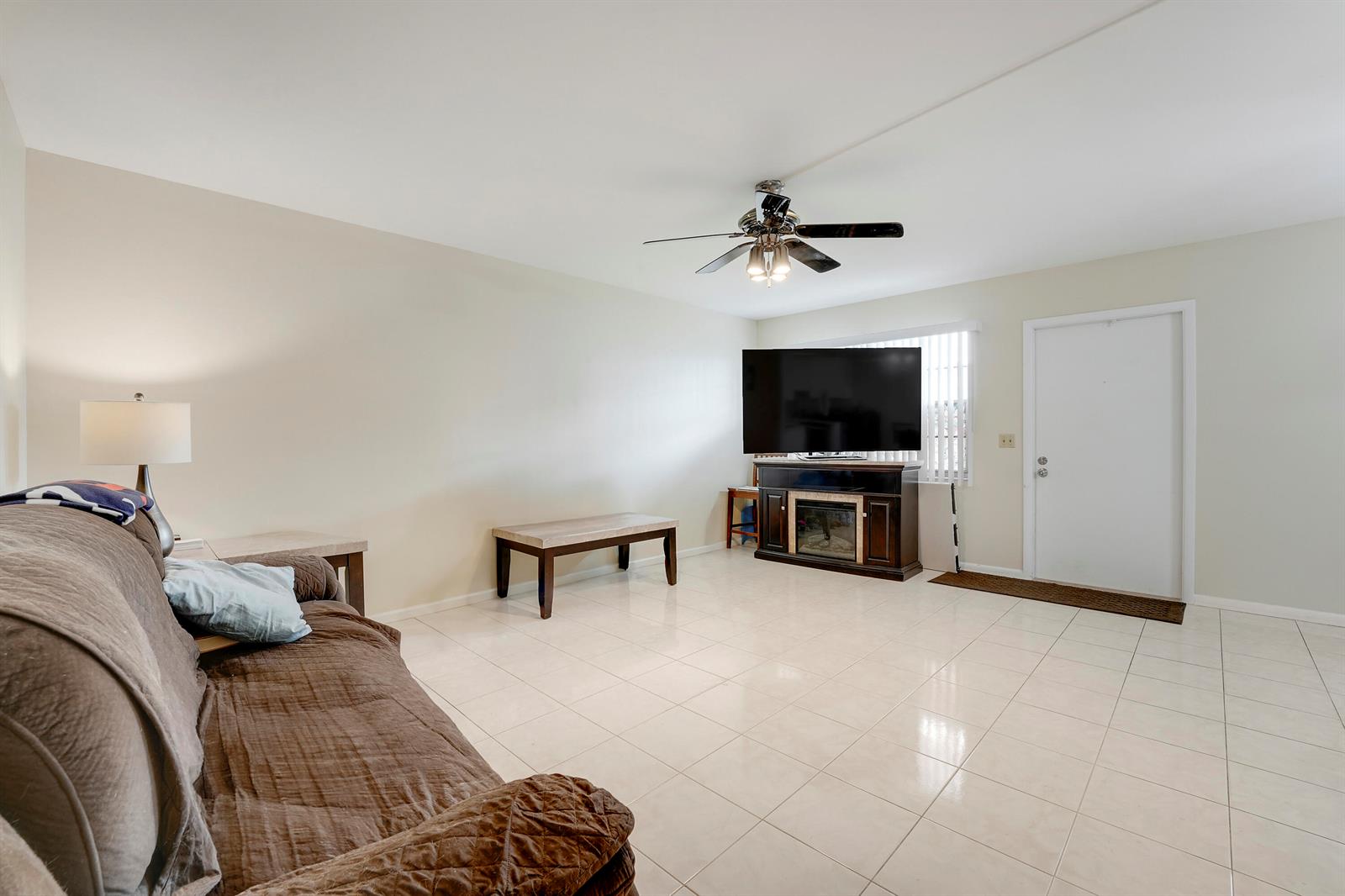 A living room features light tile flooring, a brown sofa, and a television on a stand — 1011 Exeter, Boca Raton FL 33434, BOCA RATON, FL