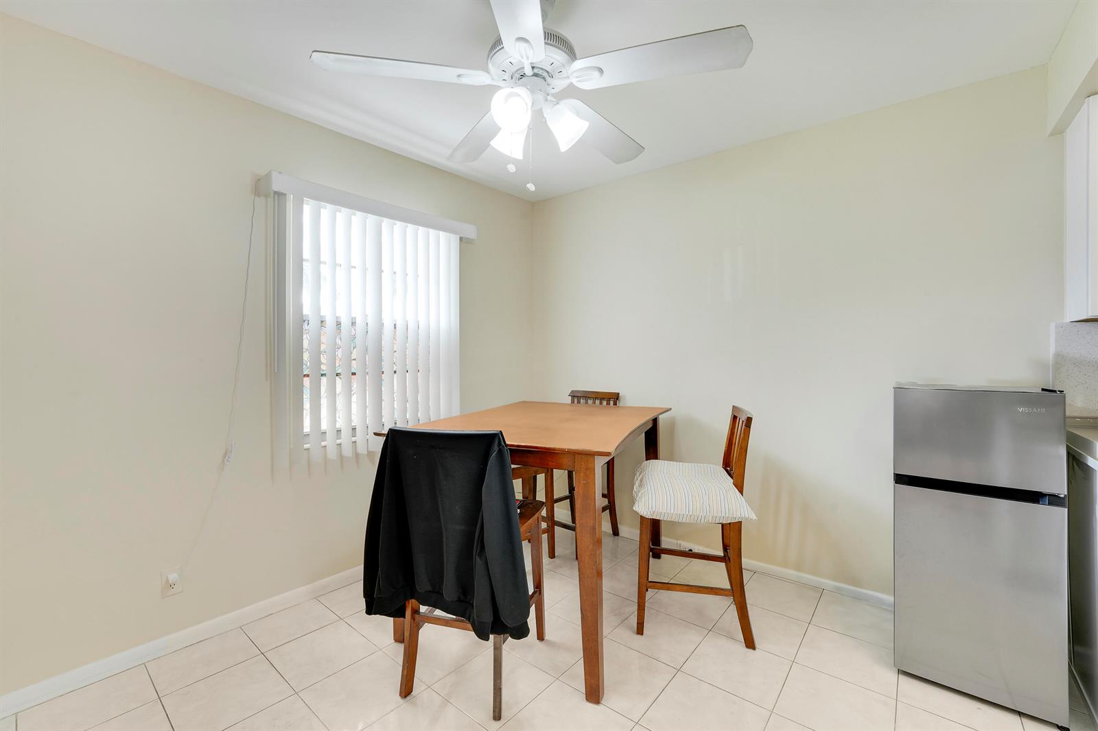 A dining area features a wooden table, two chairs, a ceiling fan, and a refrigerator — 1011 Exeter, Boca Raton FL 33434, BOCA RATON, FL