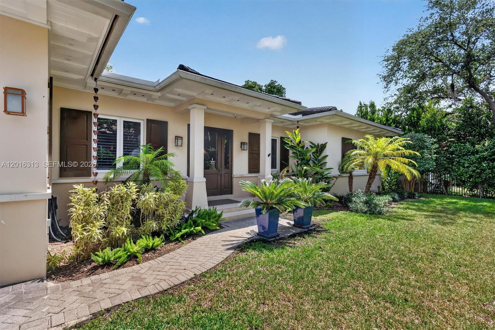 A single-story house exterior features a brick walkway, covered entryway, and tropical landscaping — 442 Amalfi Ave, Coral Gables FL 33146, CORAL GABLES, FL