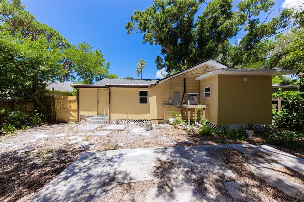 The exterior of a yellow house features a concrete patio and a wooden fence — 2240 10TH STREET S, ST PETERSBURG, FL