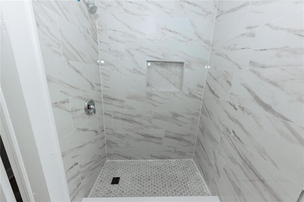 A walk-in shower features white marble-look wall tiles, a mosaic floor, and a recessed niche — 2240 10TH STREET S, ST PETERSBURG, FL