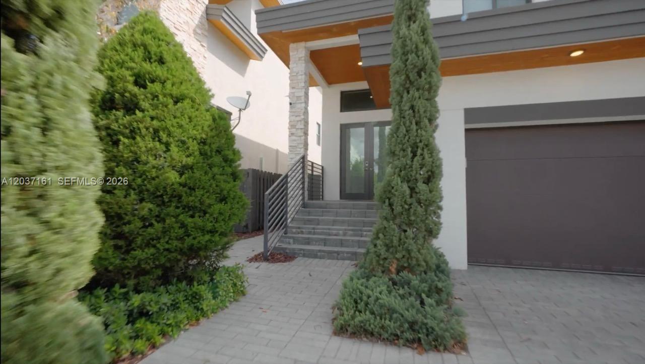 A modern house exterior features a stone pillar, a gray garage door, and front steps — 7661 NW 103rd Ct, Doral FL 33178, DORAL, FL