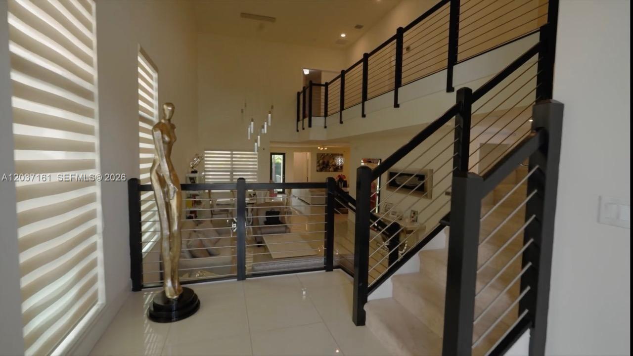 A foyer features a staircase with cable railings, a tall sculpture, and tile flooring — 7661 NW 103rd Ct, Doral FL 33178, DORAL, FL