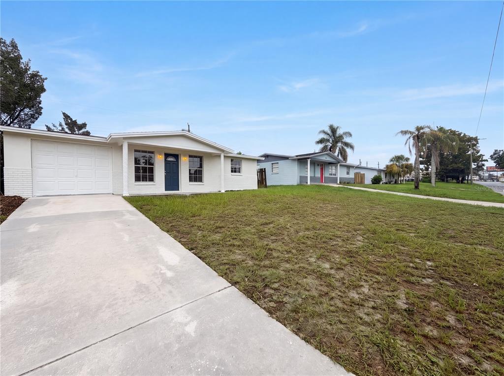 A white single-story house with a garage and a concrete driveway sits on a lawn — 4639 IRENE LOOP, NEW PORT RICHEY, FL