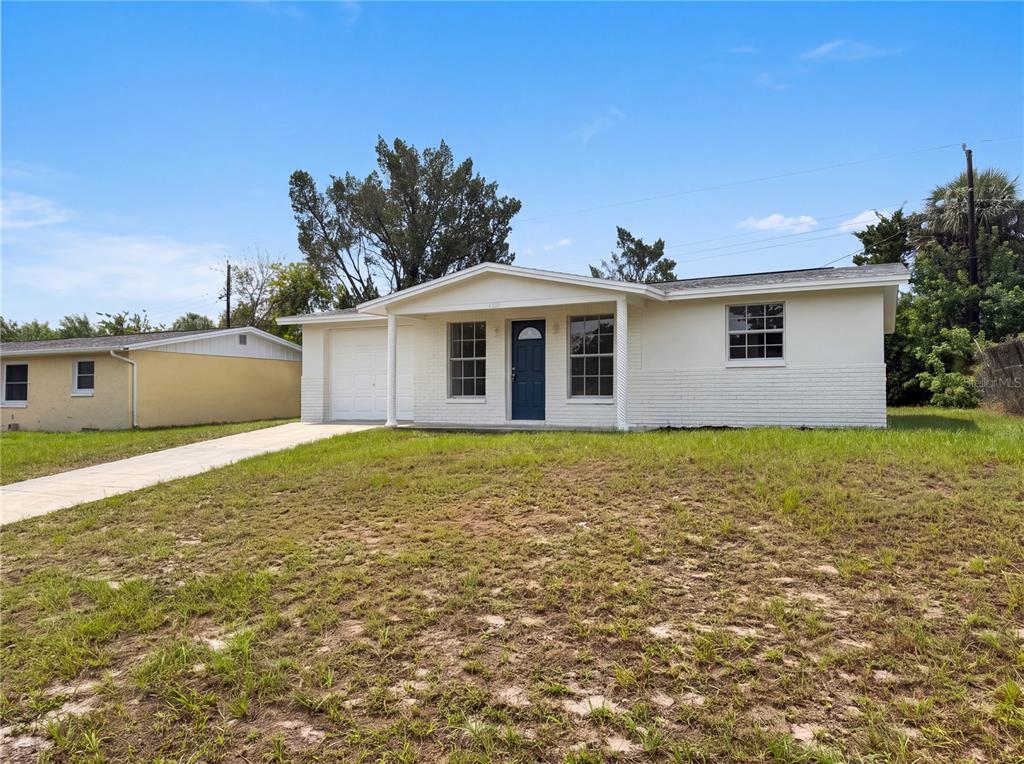 A white, single-story house with a blue front door and an attached garage — 4639 IRENE LOOP, NEW PORT RICHEY, FL
