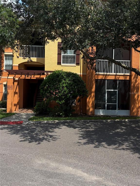 A multi-story apartment building exterior features a covered entrance, balconies, and a large central shrub — 8775 SARTORI STREET UNIT 309, ORLANDO, FL