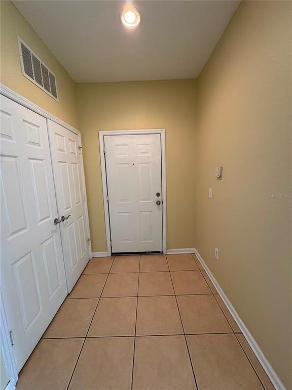 An entryway features a white door, a double-door closet, and light-colored tile flooring — 8775 SARTORI STREET UNIT 309, ORLANDO, FL