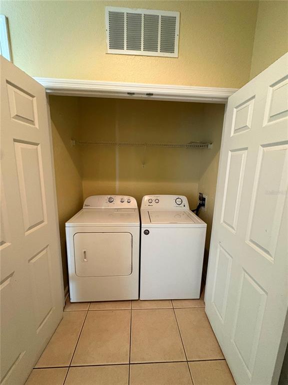A laundry closet contains a white dryer and washing machine beneath a wire shelf — 8775 SARTORI STREET UNIT 309, ORLANDO, FL