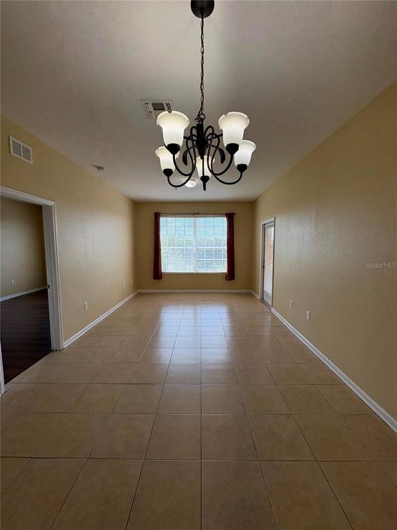 A dining room features tan tile flooring, light-colored walls, and a central chandelier — 8775 SARTORI STREET UNIT 309, ORLANDO, FL