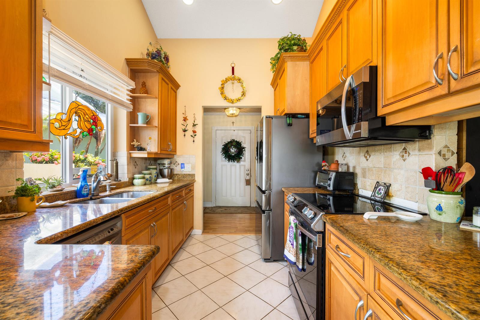 A kitchen features wood cabinets, granite countertops, stainless steel appliances, and a tiled floor — 224 Cape Pointe Circle, Jupiter FL 33477, JUPITER, FL