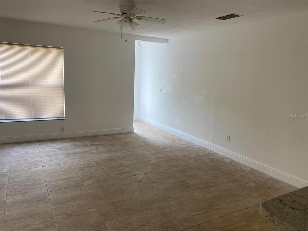 An empty room features white walls, tan tile flooring, and a ceiling fan — 5452 E MICHIGAN STREET UNIT 5452-1, ORLANDO, FL