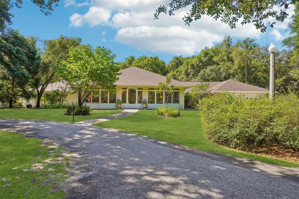A single-story house with a gravel driveway, large windows, and a sprawling lawn — 4546 GRIFFIN VIEW DRIVE, LADY LAKE, FL