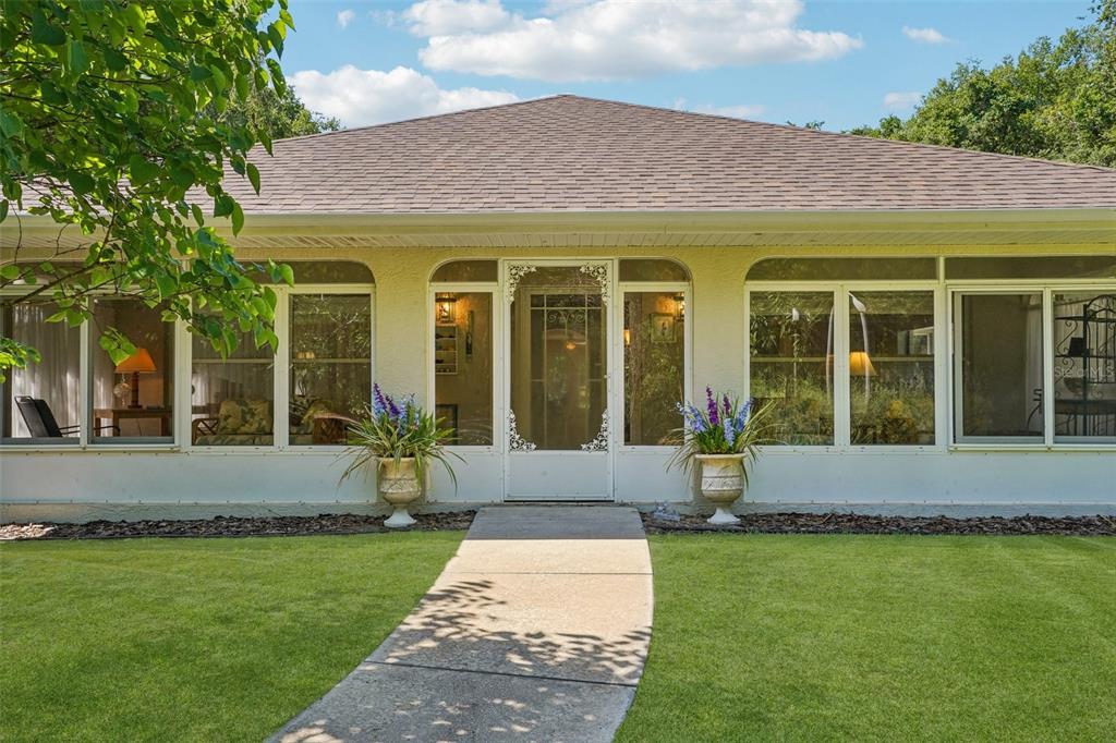 A single-story house with a screened-in front porch, a central door, and a concrete walkway — 4546 GRIFFIN VIEW DRIVE, LADY LAKE, FL