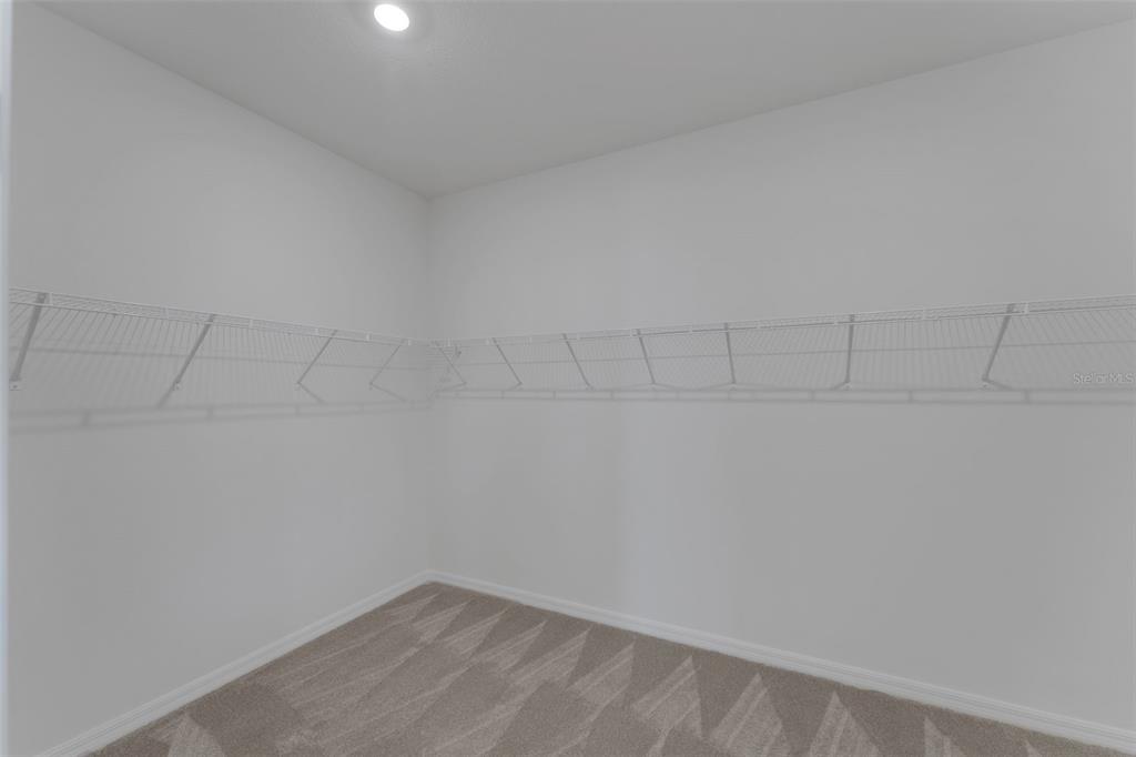 A walk-in closet features white wire shelving, light gray carpet, and white walls — 17013 GREAT HERON LANE, PUNTA GORDA, FL
